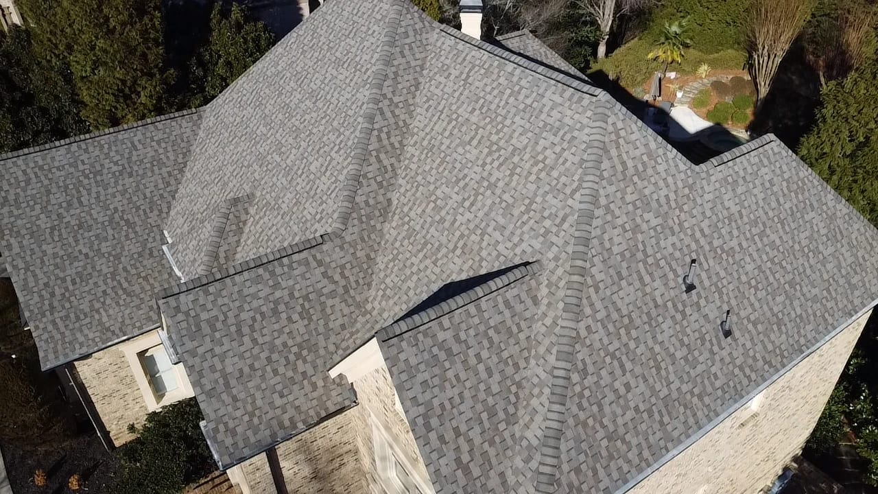 Close aerial view of a freshly installed light gray architectural shingle roof