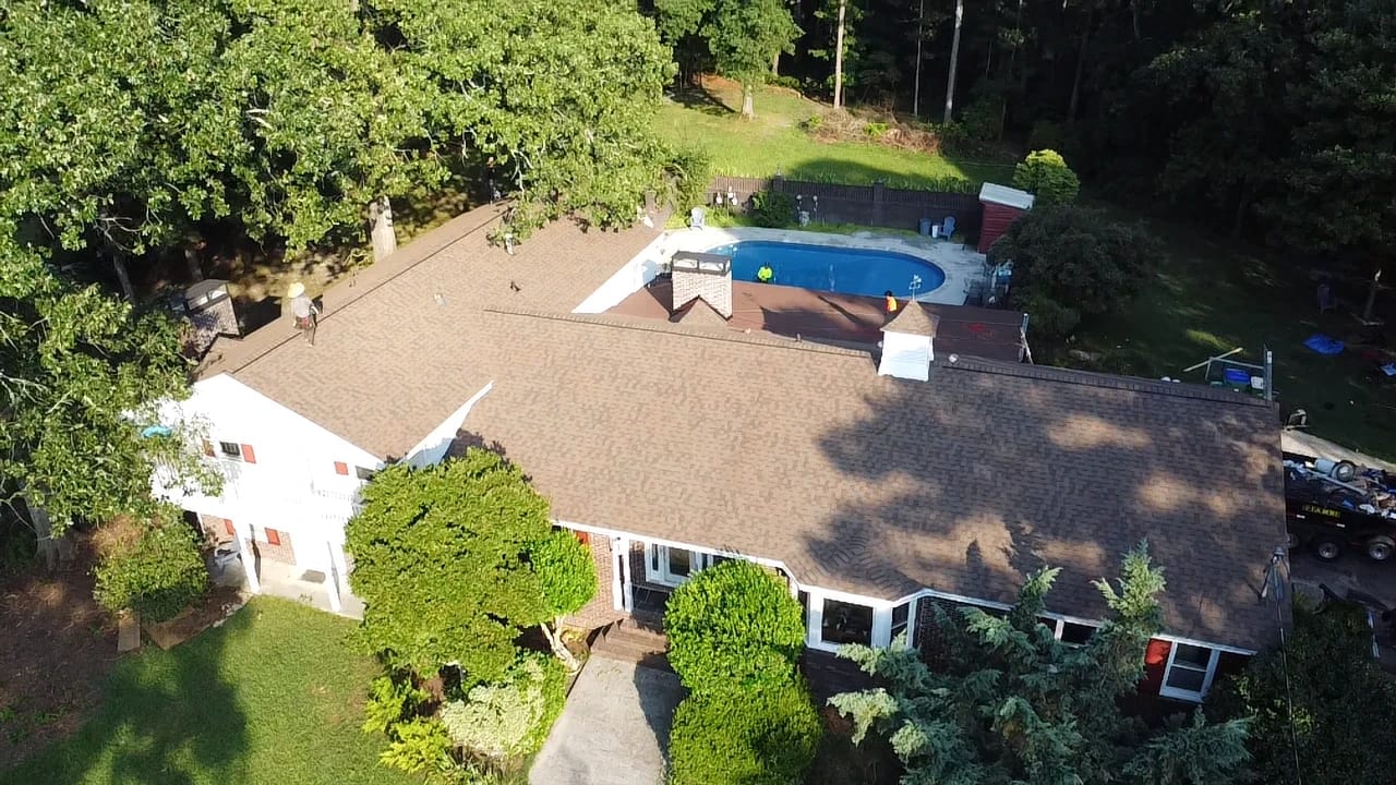 Aerial view of a tan shingle roof on a ranch home with a backyard pool