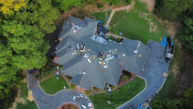 Aerial view of a roof replacement in progress with materials staged on the rooftop