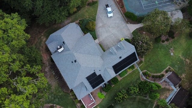 Aerial view of a light gray shingle roof with rooftop solar panels